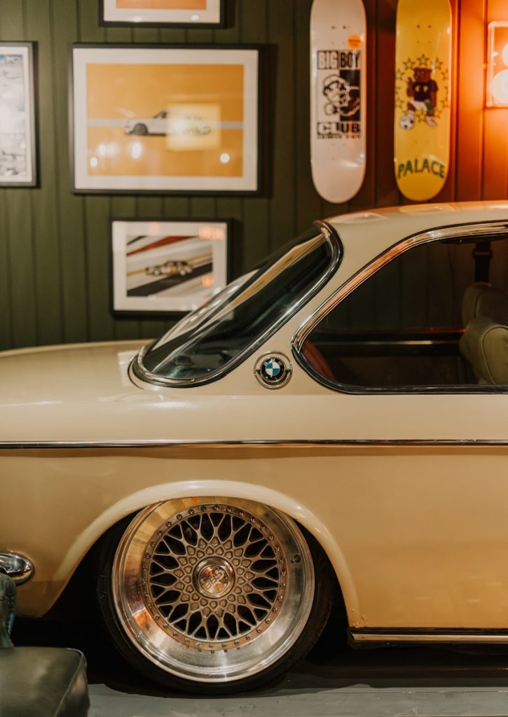 Vintage BMW with skateboards and wall art.